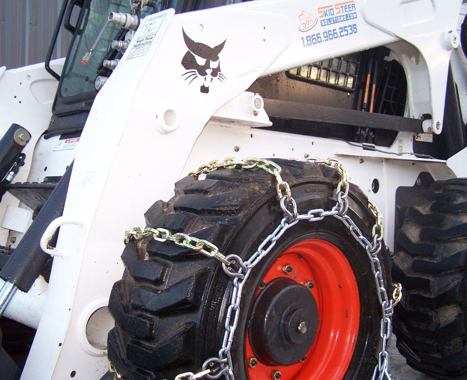angled view of a skid steer tire with chains attached to it