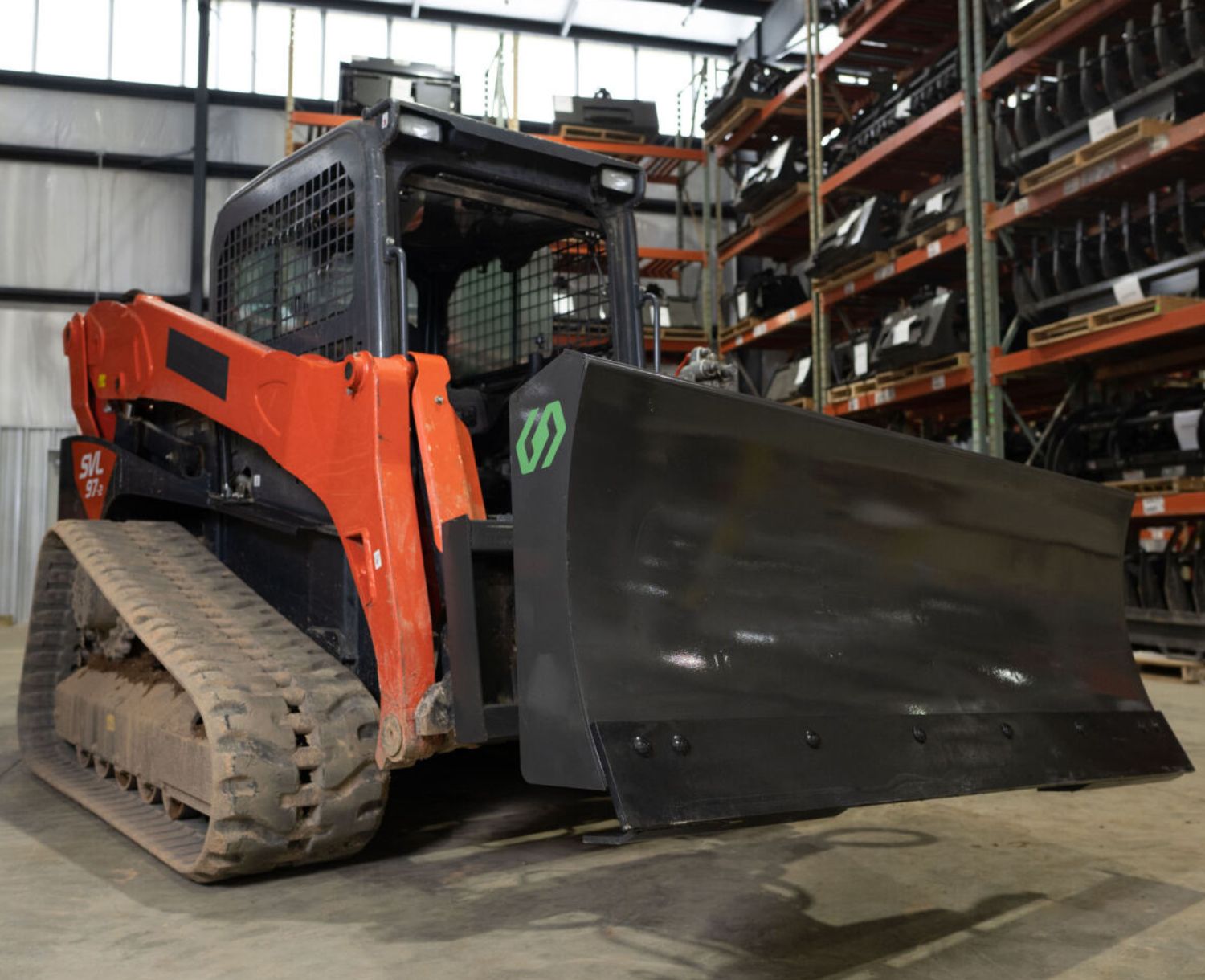 angled view of a skid steer parked in a warehouse with a cid 6 way angle blade attached to the front