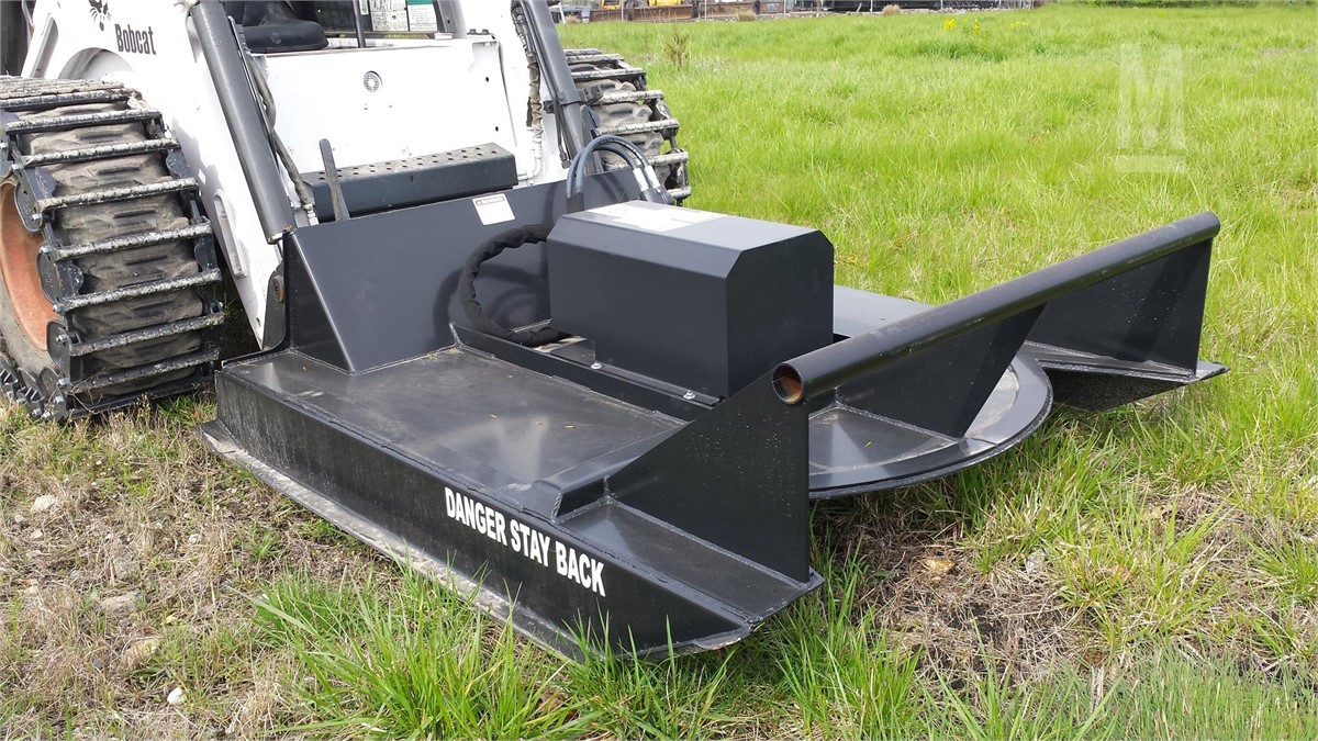 left angled view of a skid steer parked on grass with a cid skid steer brush cutter attachment mounted on the front