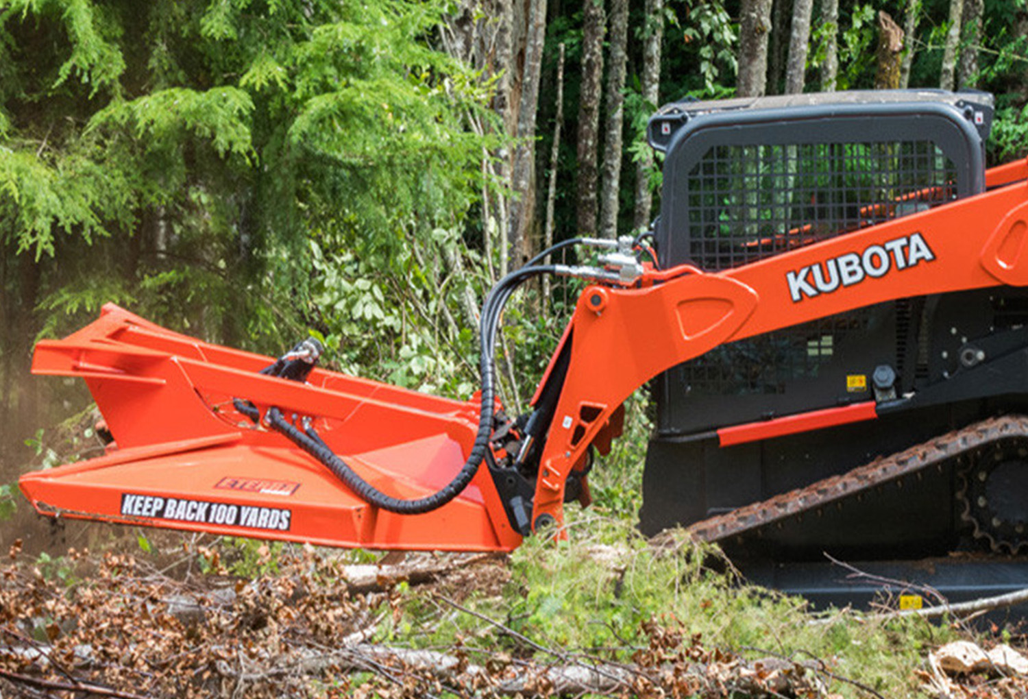 left angled view of a skid steer parked in a forested area with an eterra skid steer typhoon clearing mower attachment on the front