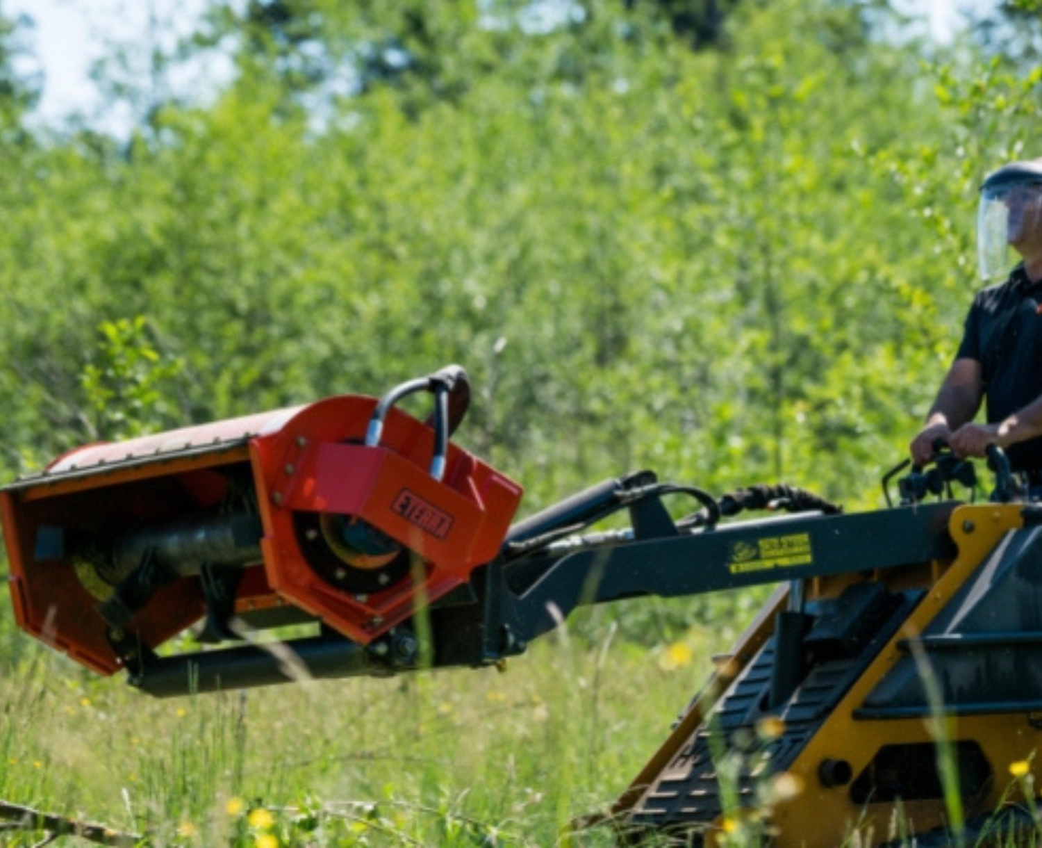 righ aide angled view of a mini skid steer in a forested area with an eterra mini skid steer sidewinder flail mower attachment on the front