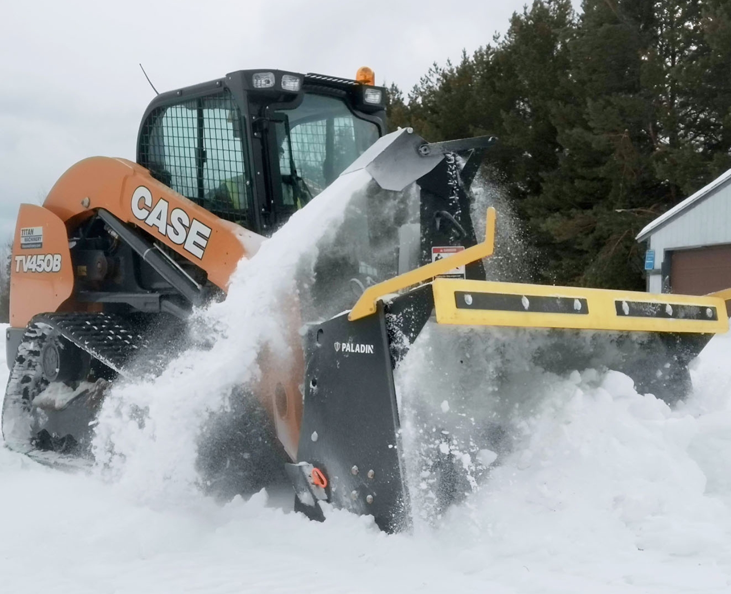 angled shot of a skid steer with a paladin skid steer ice shark blowing snow
