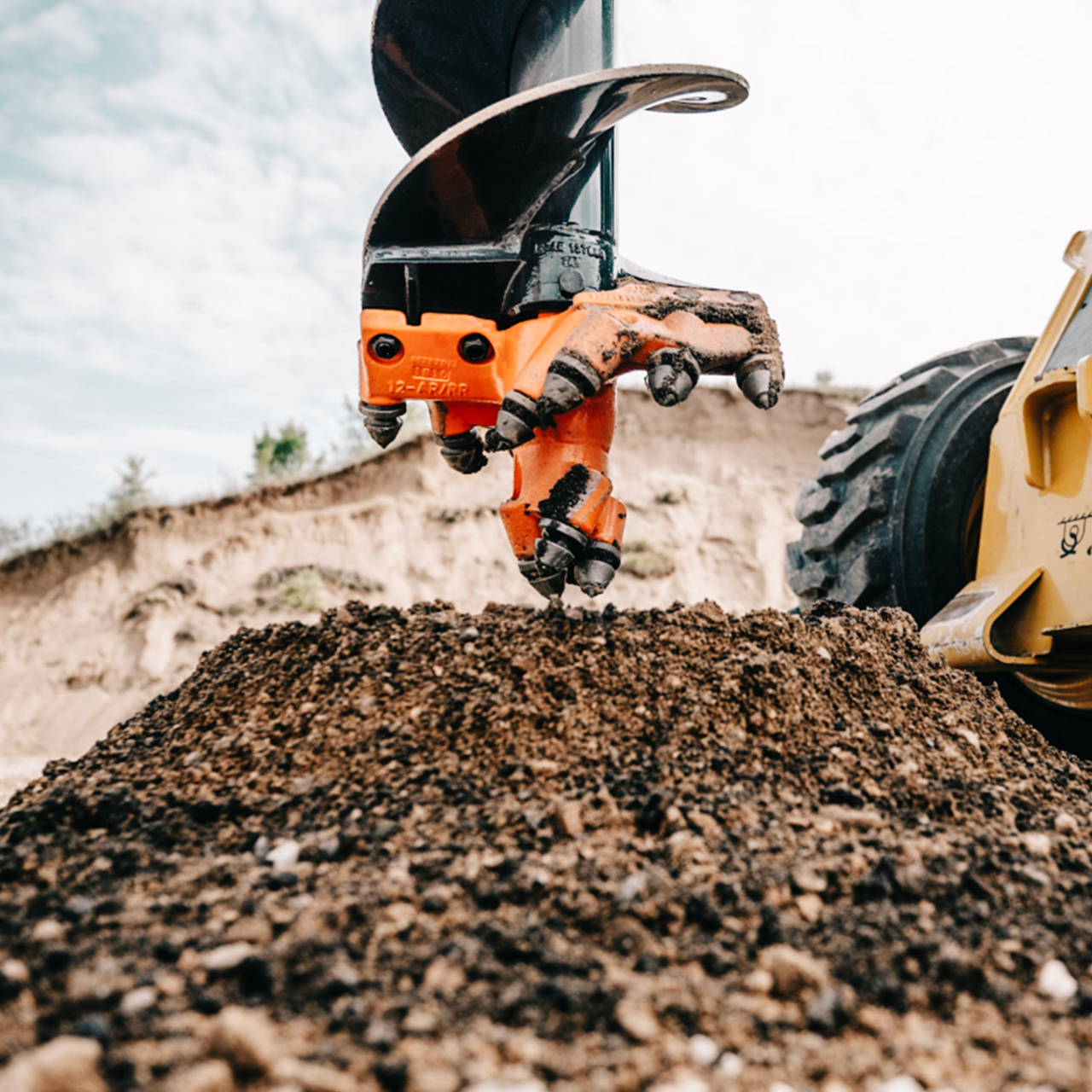 closeup shot of a pengo skid steer auger bit drilling into the dirt