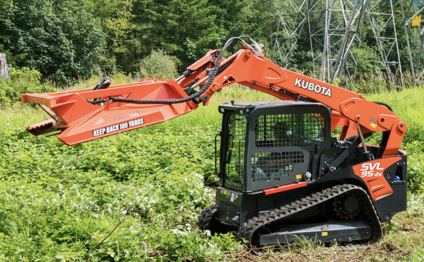 right side profile of a skid steer parked in a forested area with an eterra skid steer typhoon clearing ower attachment on the front lifted up