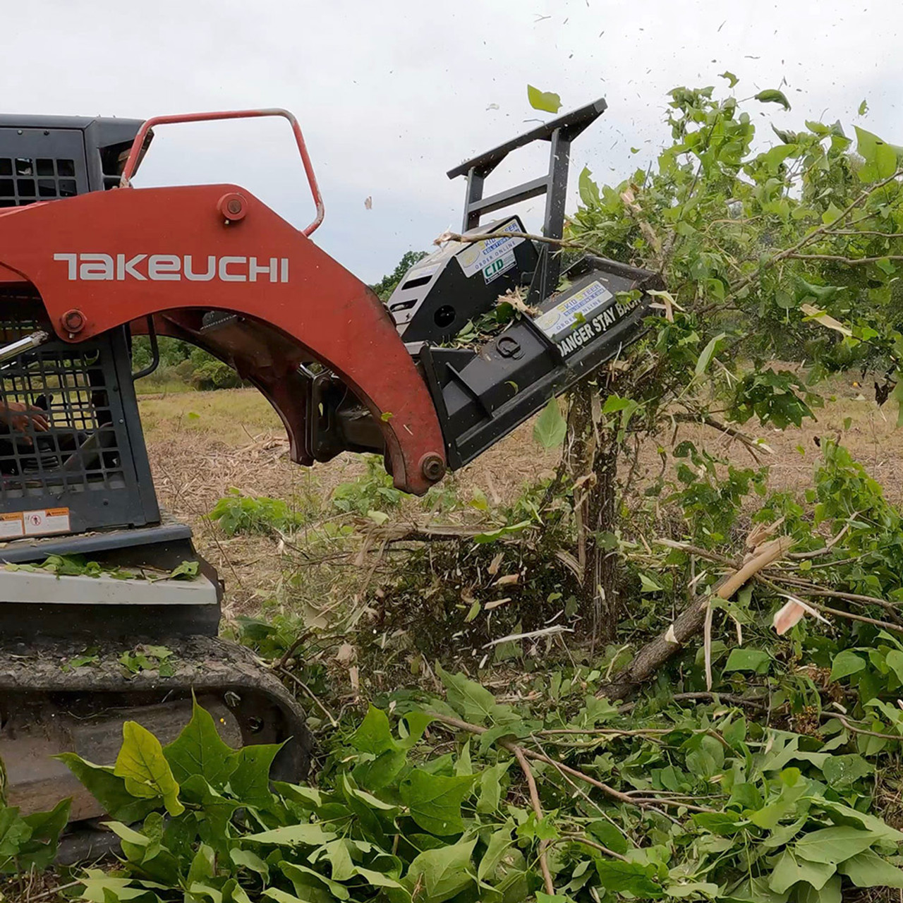 front left side view of a skid steer parked in a forested area 