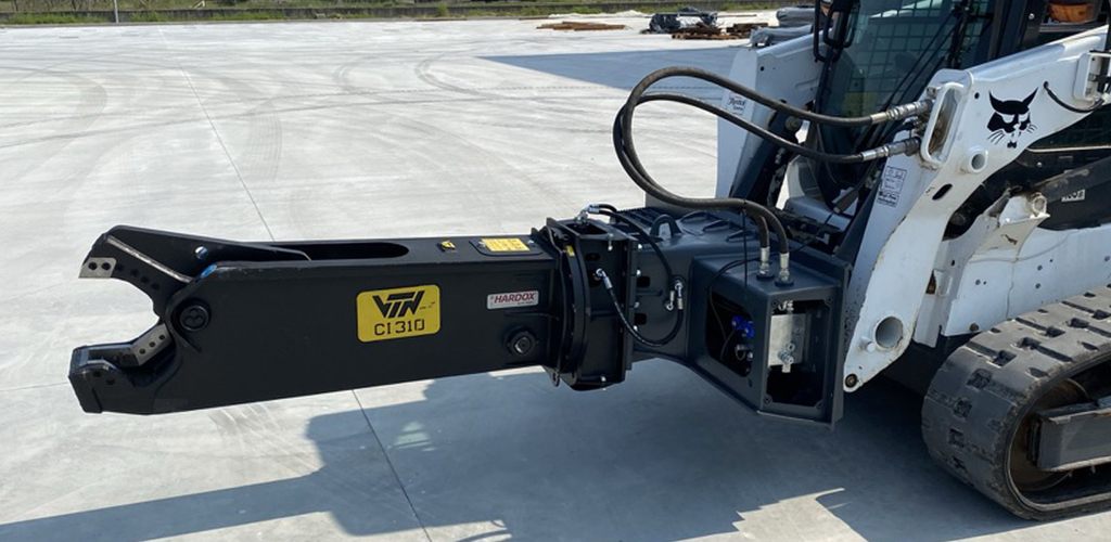 side profile view of a skid steer parked on concrete with a VTN scrap shear attachment on the front